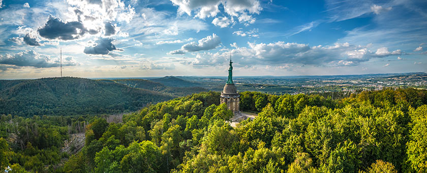 Das Hermannsdenkmal ragt zwischen den Bäumen hervor.