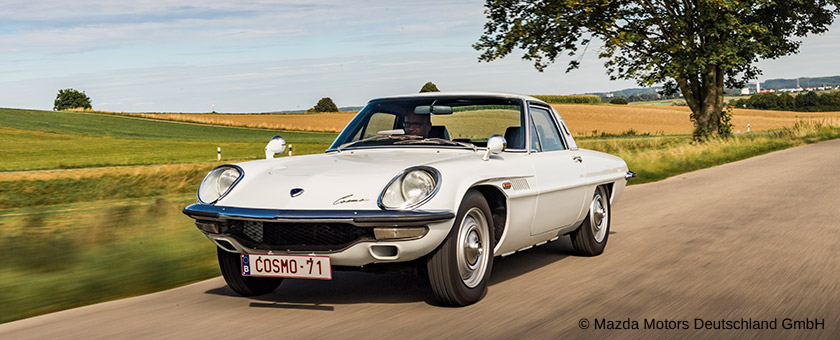Ein Oldtimer von Mazda fährt über eine Landstraße.
